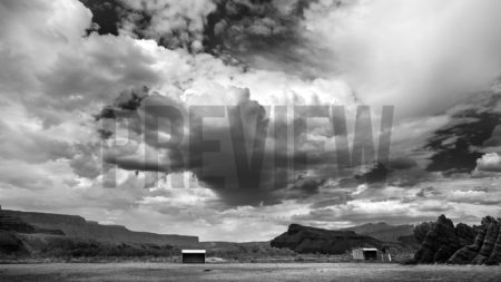 A black and white stock photograph of clouds over a ranch.
